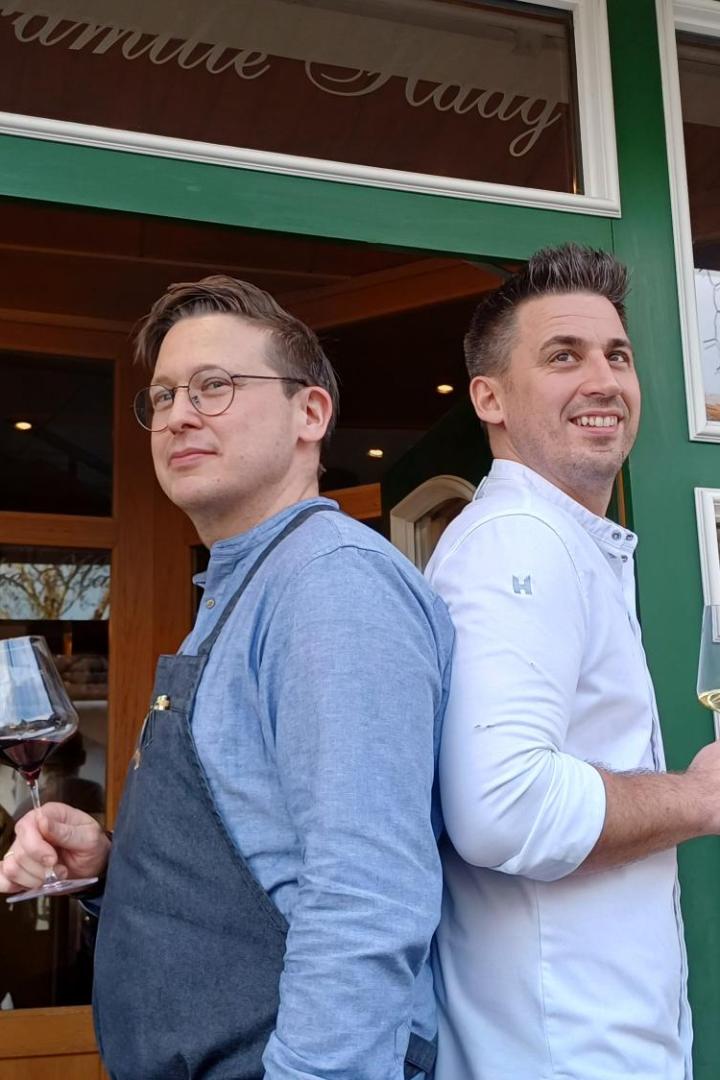 Markus und Thomas Haag mit einem Weinglas in der Hand vor ihrem Wirtshaus.  