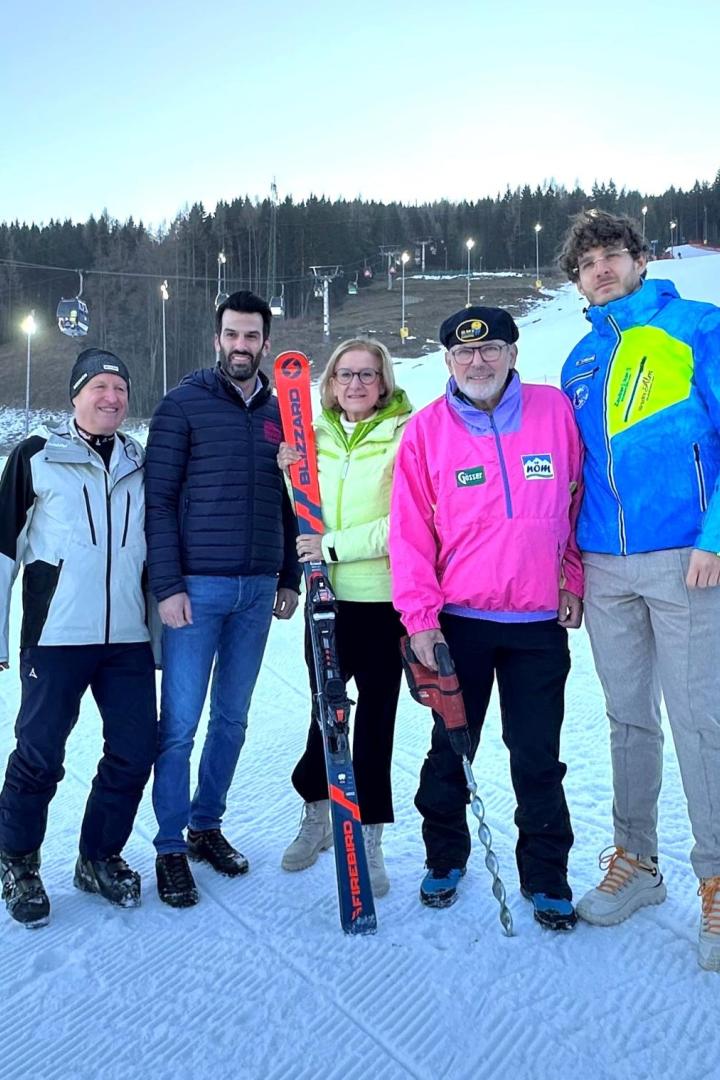 Fünf Personen stehen auf einer Skipiste.