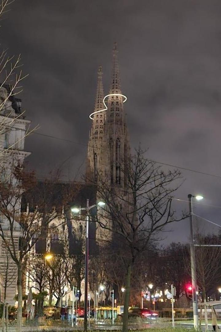 Die Votivkirche bei Nacht mit leuchtender Infinity-Lichtinstallation zwischen den Türmen.