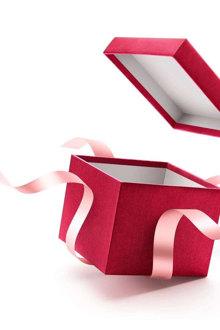 Eine offene, rote Geschenkbox mit rosa Schleifen schwebt vor einem weißen Hintergrund.
