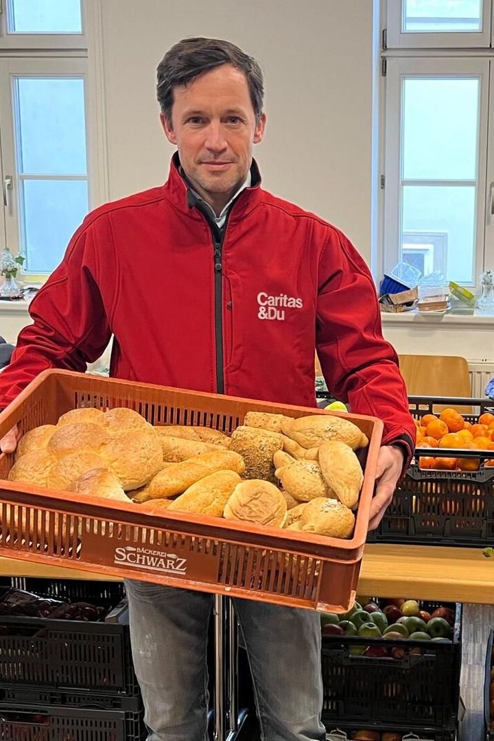 Klaus Schwertner hält bei der Lebensmittelausgabe eine Box mit Broten.