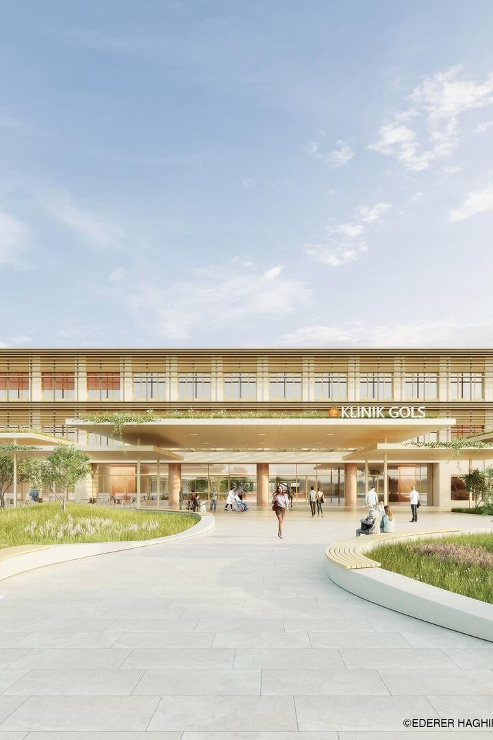 Moderne Klinik mit großer Glasfassade, umgeben von Grünflächen, Menschen sitzen und gehen auf dem Vorplatz, ein Rettungswagen steht rechts.