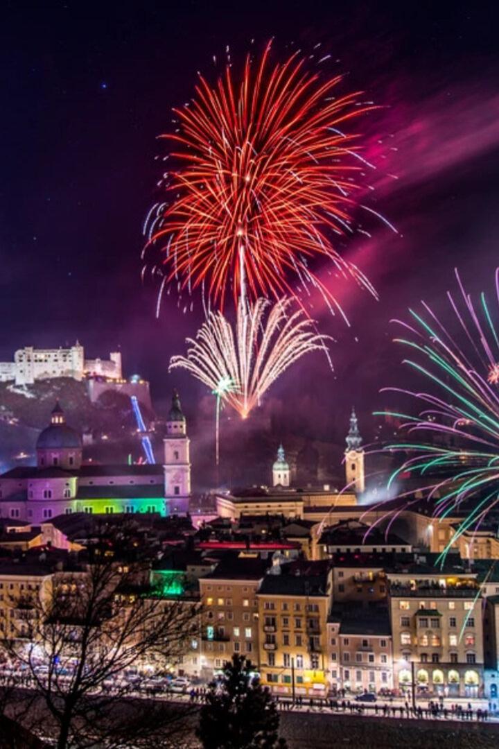 Über Salzburg leuchten bunte Feuerwerke am Nachthimmel, die Festung Hohensalzburg ist im Hintergrund erkennbar.
