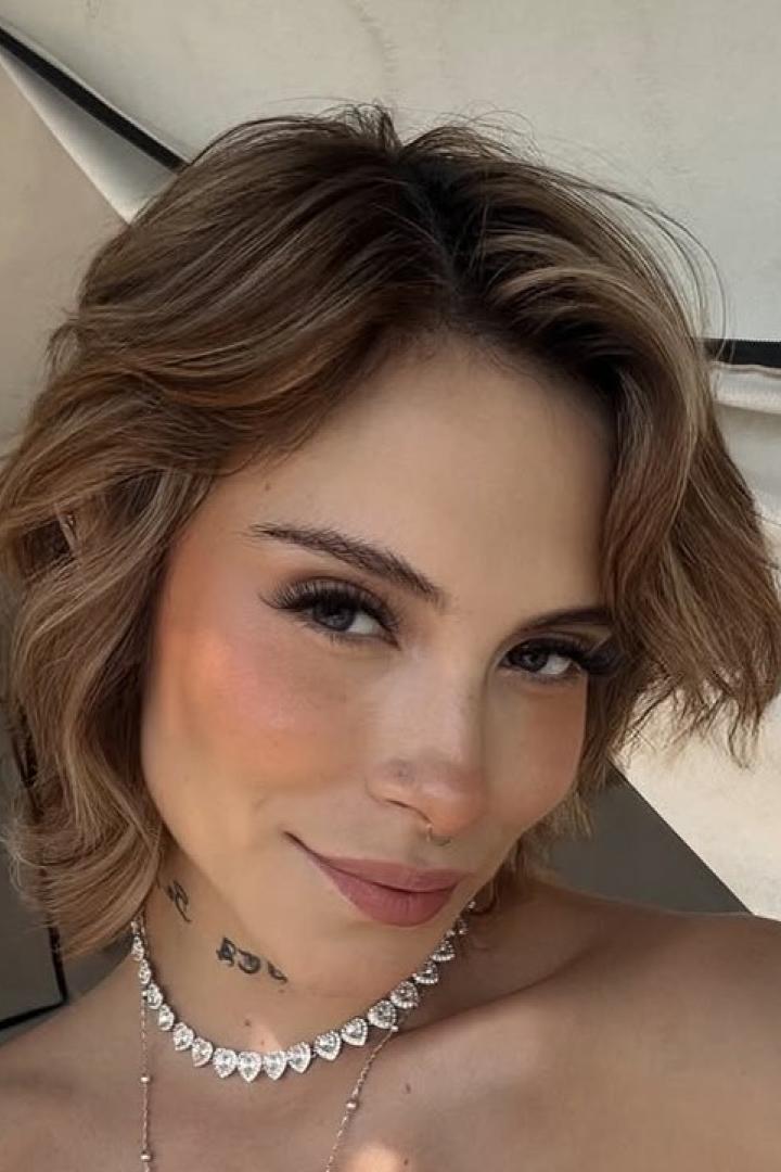 28-jährige Frau mit kurzen blonden Haaren lächelt in die Kamera für ein Selfie