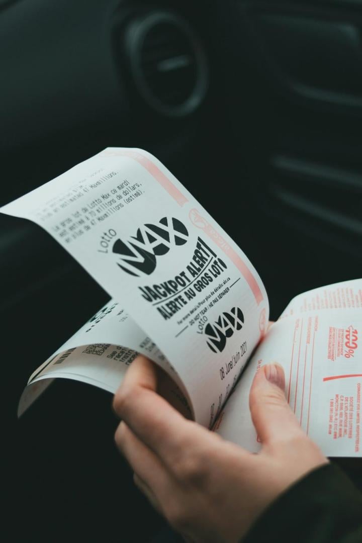 Eine Person hält mehrere Lottoscheine in der Hand.