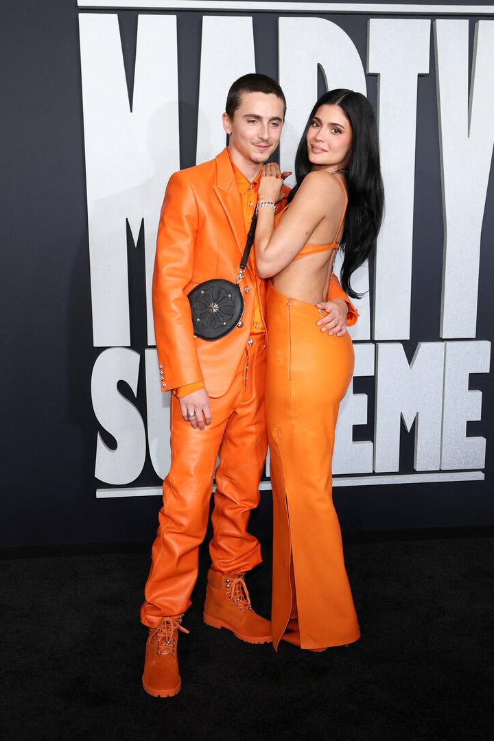 Timothée Chalamet und Kylie Jenner posieren gemeinsam in oranger Kleidung.