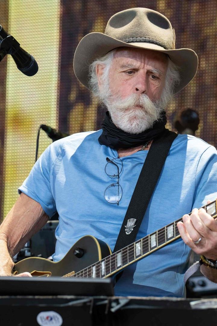 Bob Weir mit Hut und Bart spielt Gitarre auf einer Bühne.