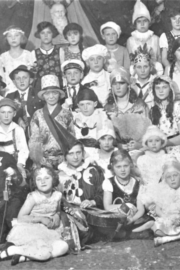 Viele Kinder in fantasievollen Kostümen sitzen und stehen in mehreren Reihen für ein Gruppenporträt zusammen.