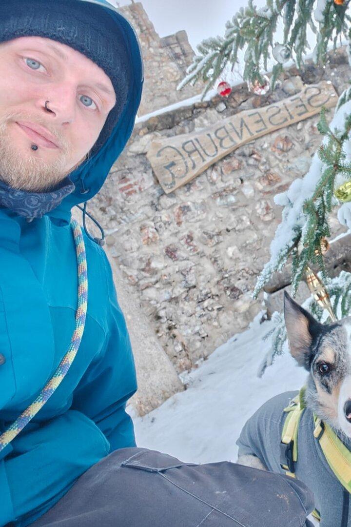 Ein Mann mit einem Hund schaut in die Kamera