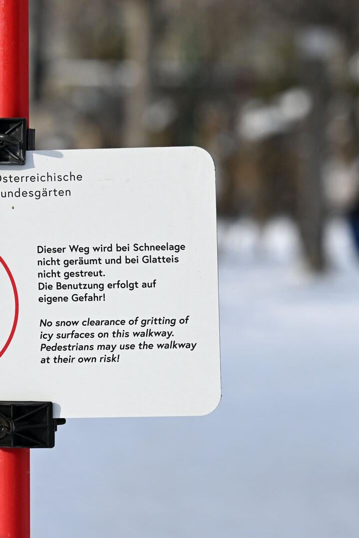 Warnschild weist auf Rutschgefahr bei Schnee und Eis hin, Nutzung des Weges erfolgt auf eigene Gefahr.
