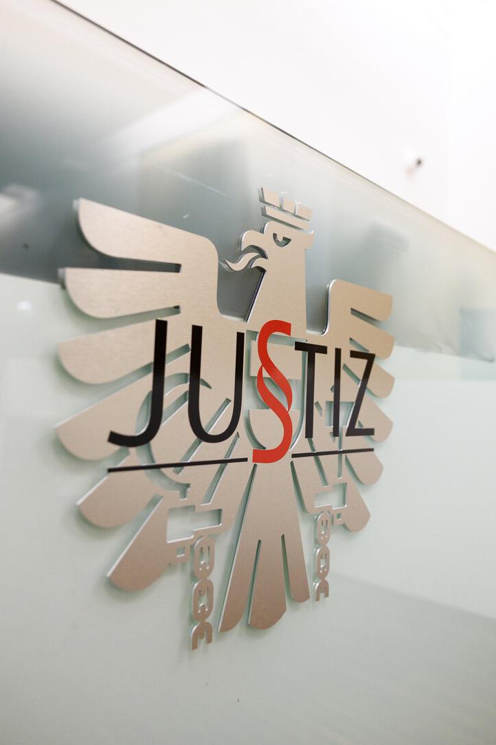 Adler mit dem Justiz-Schriftzug an der Wand eines Gerichtssaales.