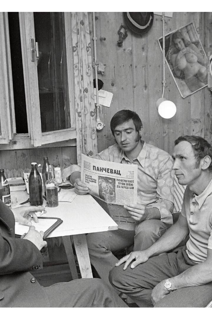 Drei Männer sitzen um einen Tisch in einer Arbeiterunterkunft.