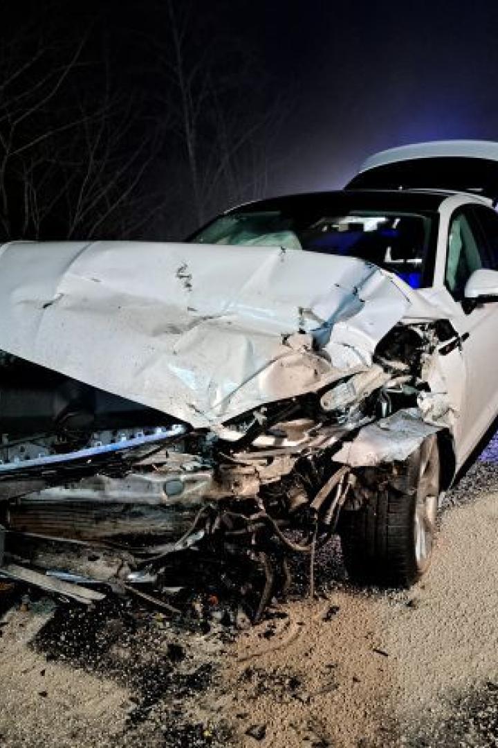 Stark beschädigtes weißes Auto nach Frontalzusammenstoß auf winterlicher Landstraße.