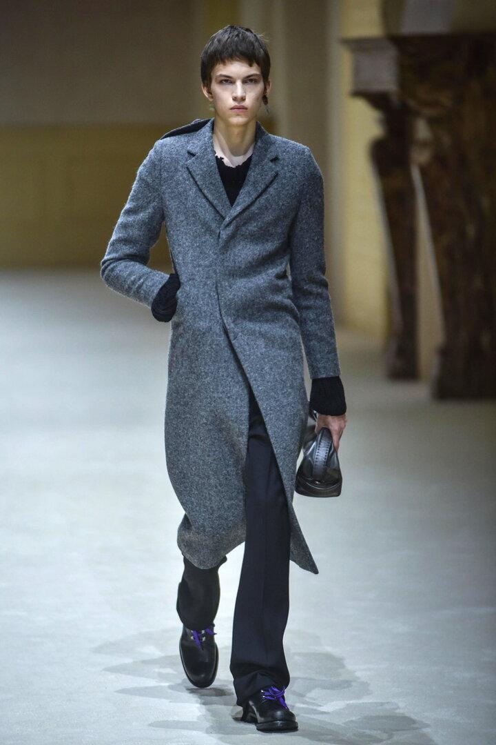 Ein sehr dünner Mann im Mantel bei der Prada Show
