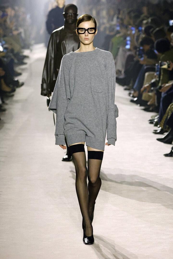 Model im langen grauen Pulli mit halterlosen Strümpfen auf dem Laufsteg