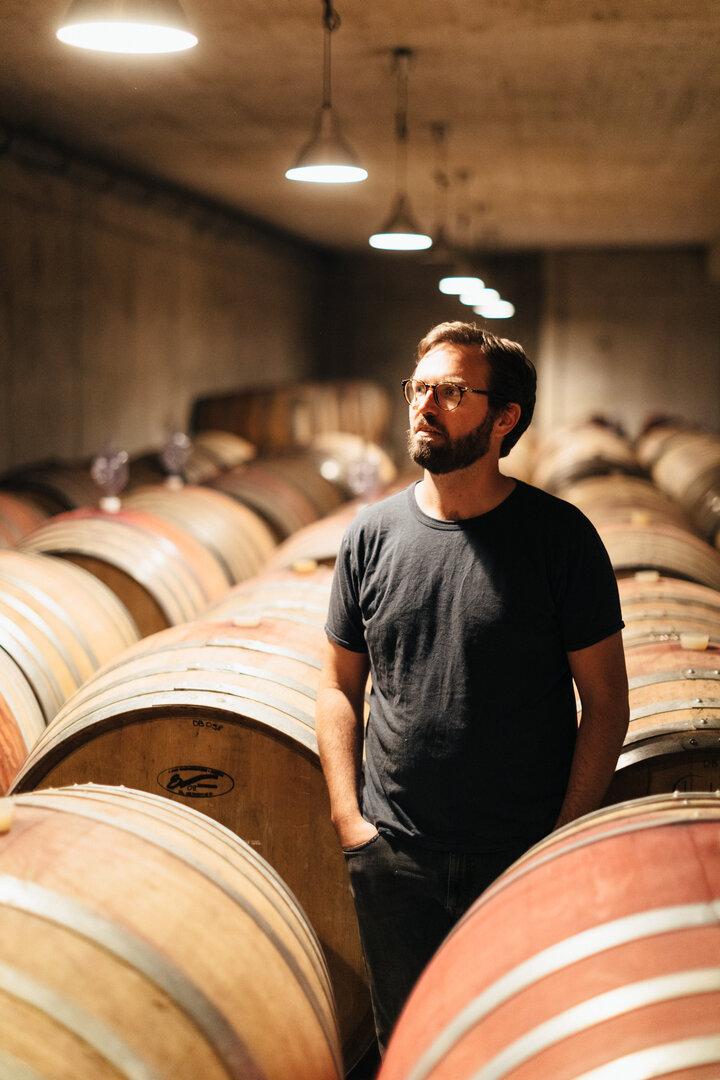 Winzer Franz Weninger steht in seinem Weinkeller zwischen Fässern