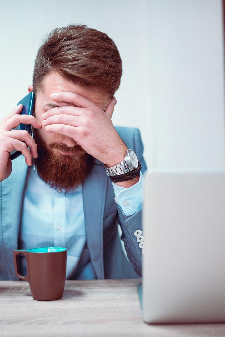 Worried and Exhausted Businessman Talking on Phone in his Office