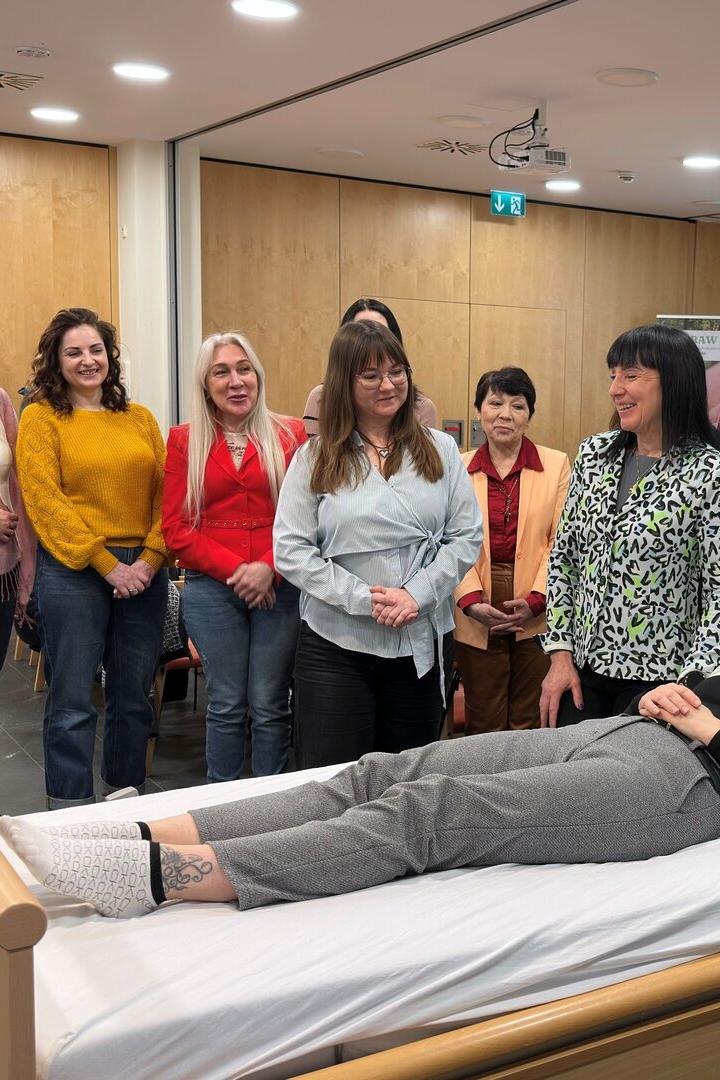 Mehrere Personen stehen um ein Bett herum