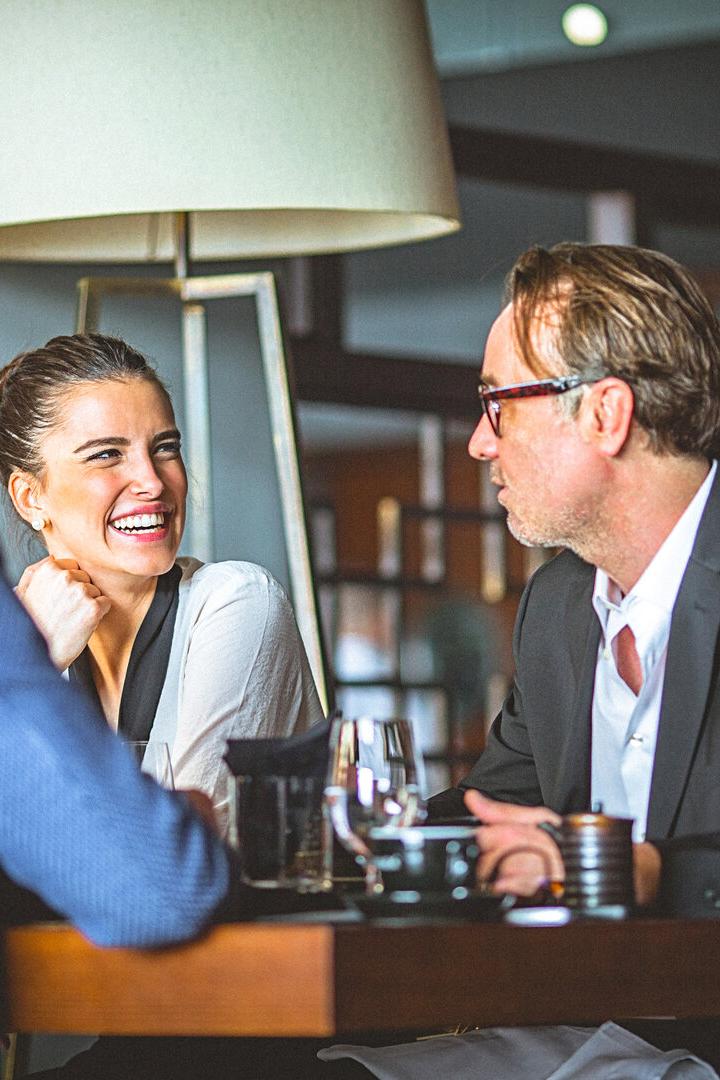 Drei Personen sitzen an einem Tisch in einem Restaurant und unterhalten sich.