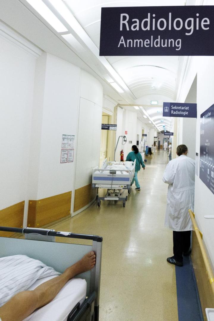 Ein Krankenhausflur mit Patientenliegen und Hinweisschildern zur Radiologie.