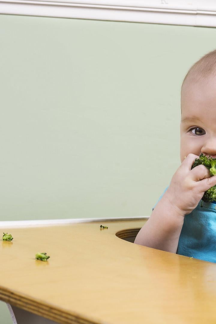 Ein Baby isst Brokkoli.