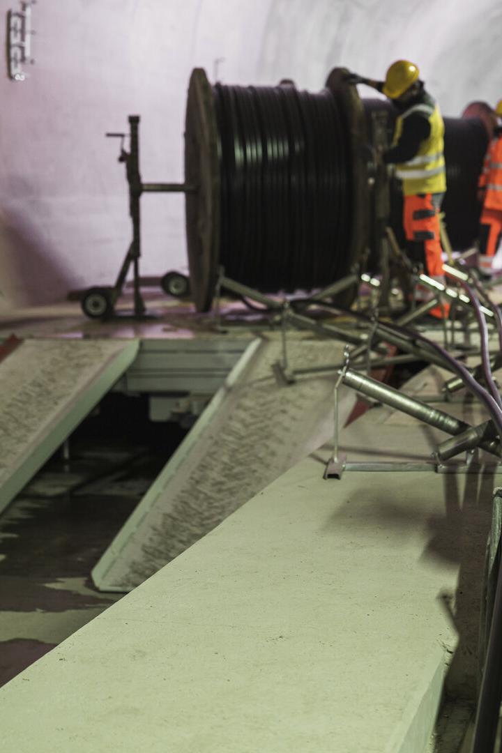 Arbeiter in orangener Kleidung bei den Arbeiten im Tunnel.