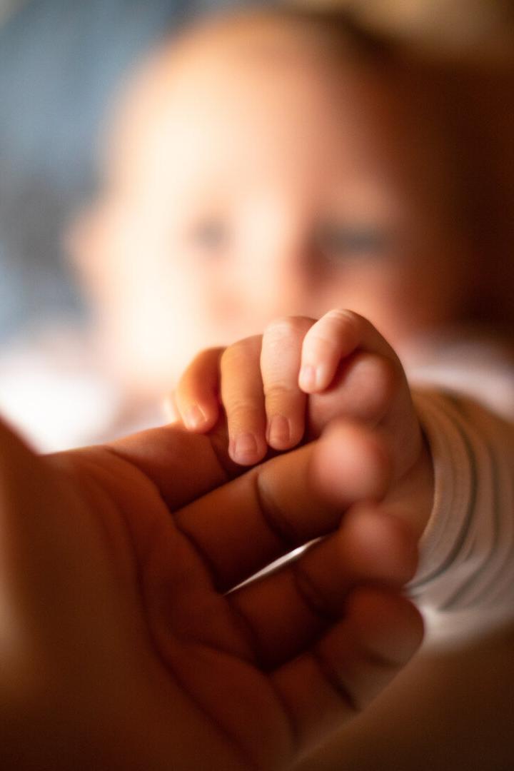 Hand holding newborn baby's hand