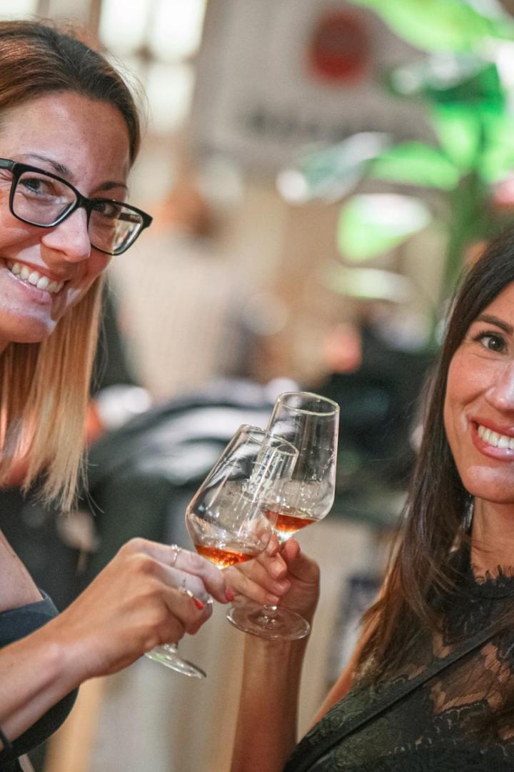 Zwei Frauen prosten sich zu und lächeln in die Kamera