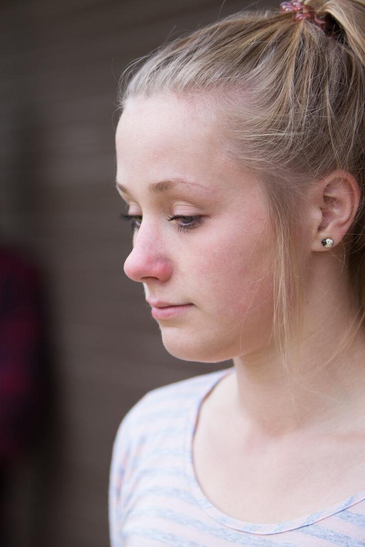 Ein Mädchen mit blondem Pferdeschwanz blickt traurig nach unten.