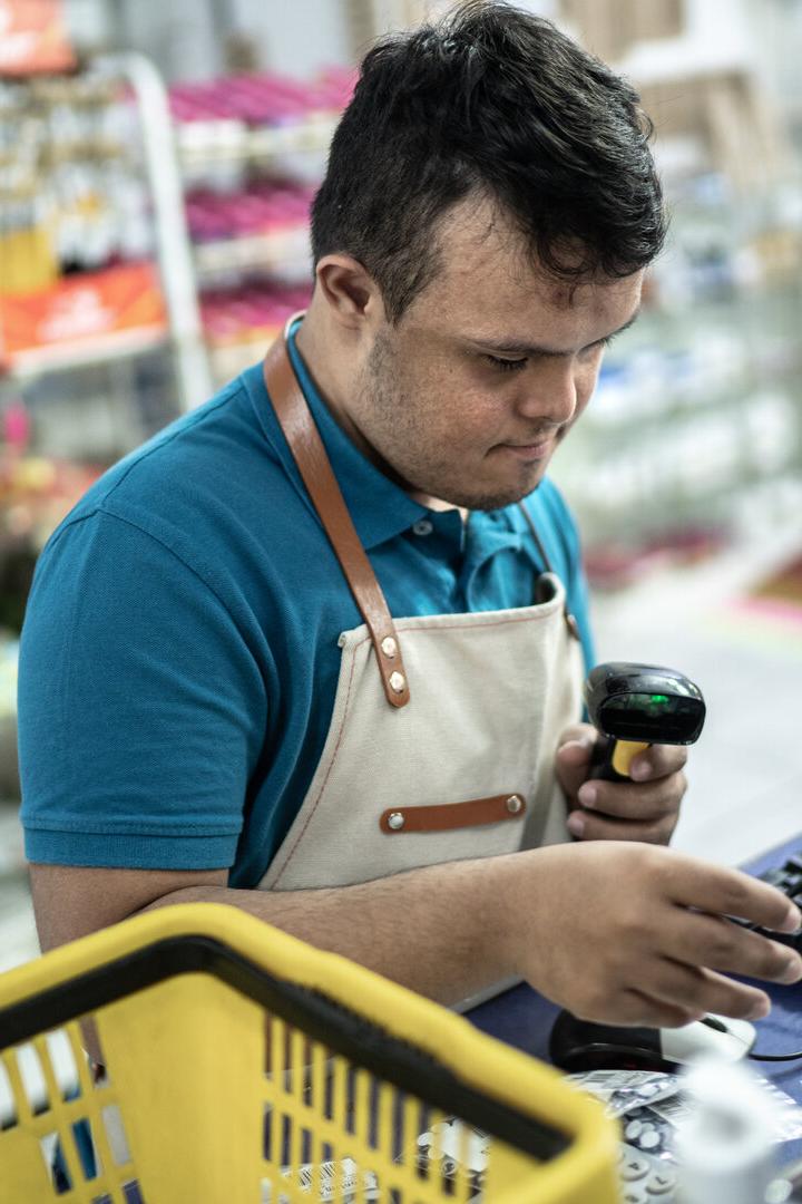 Mitarbeiter in einer Drogerie scannt Waren an der Kasse und tippt am Computer.