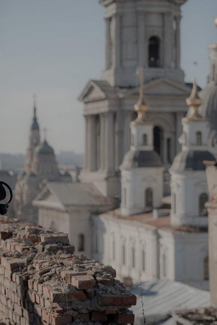 Eine Frau auf einem Dach schaut auf ein zerstörtes Gebäude