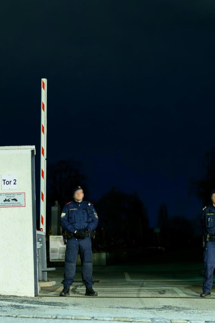 Zwei Polizisten stehen vor einem Friedhofstor.