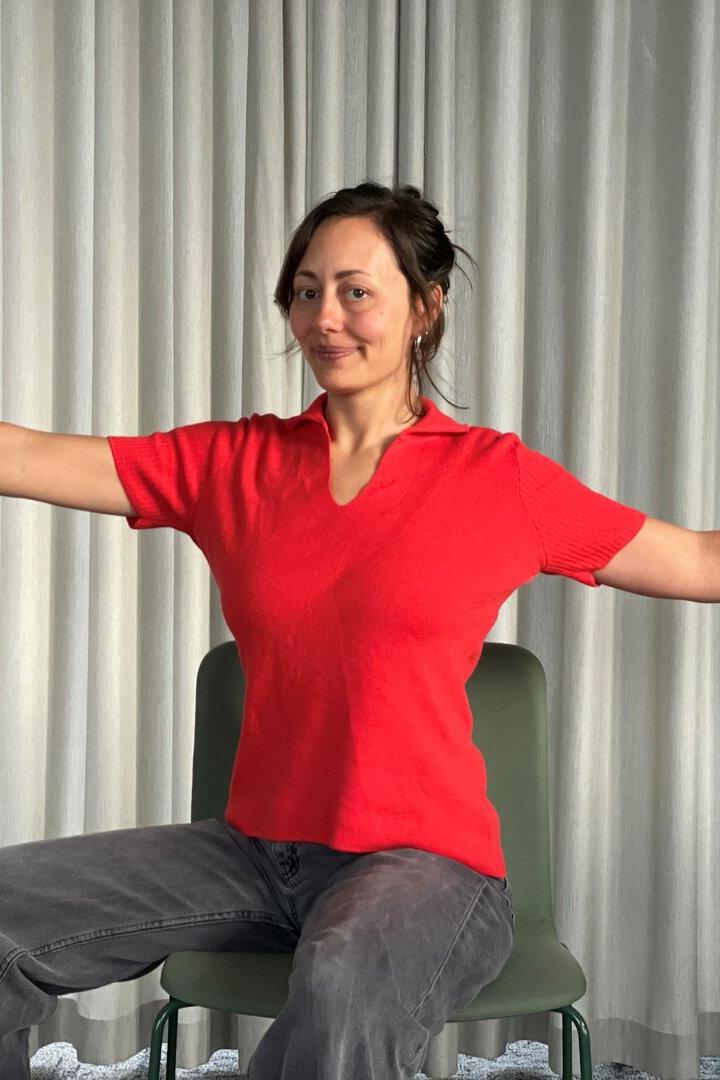 Hannah Molcar sitzt auf einem Sessel und zeigt eine Yoga-Übung vor.