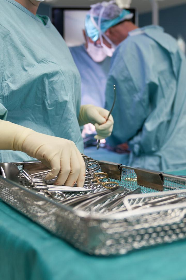 Chirurgisches Team in OP-Kleidung arbeitet mit sterilen Instrumenten an einem Operationstisch.