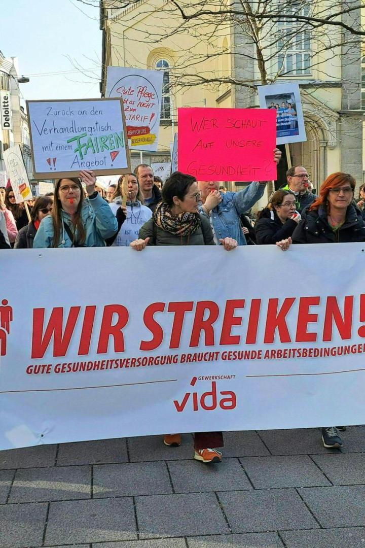 Menschenmenge mit einem Transparent mit der Aufschrift "Wir streiken"