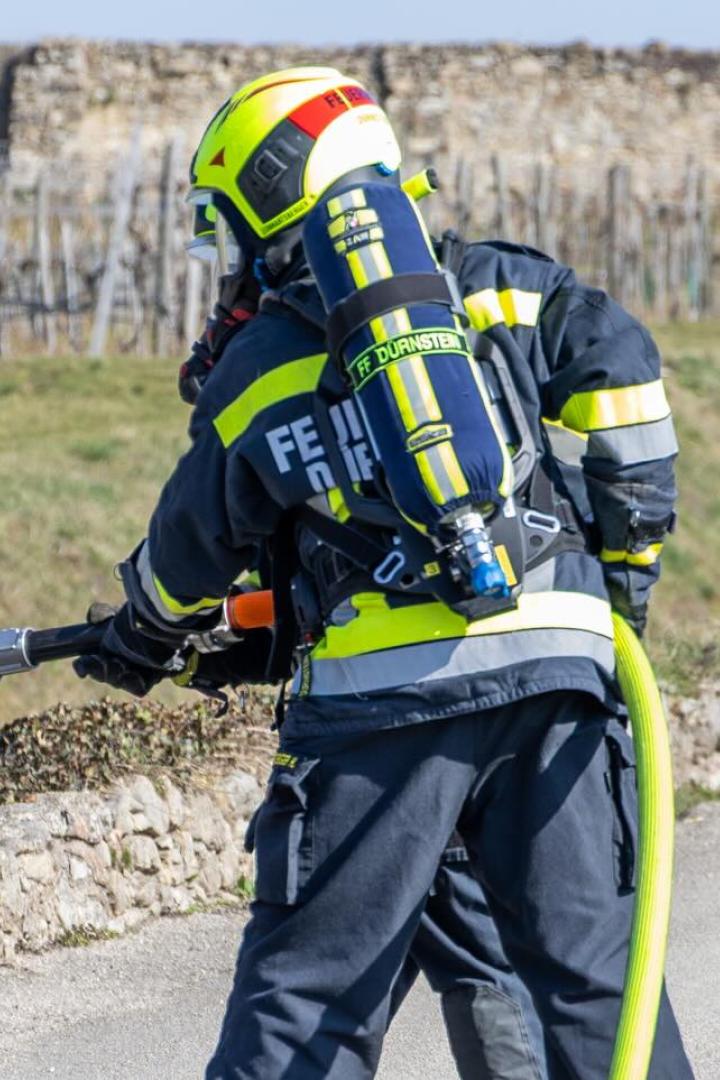 Eine Feuerwehrperson von hinten bei den Löscharbeiten.