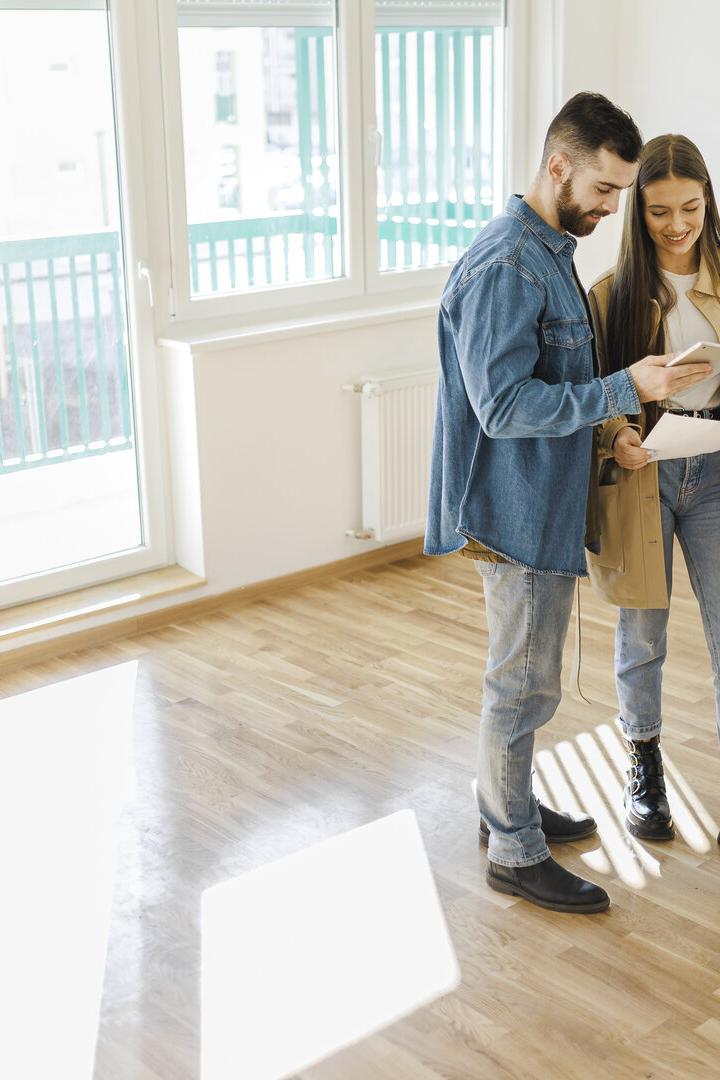 Happy family couple discussing interior design of new apartment, Man Talking With Woman In Empty Room Of New House