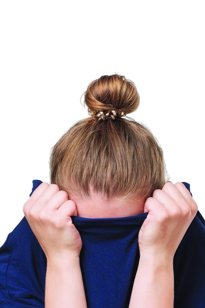 Eine Frau versteckt ihr Gesicht unter einem Pullover.