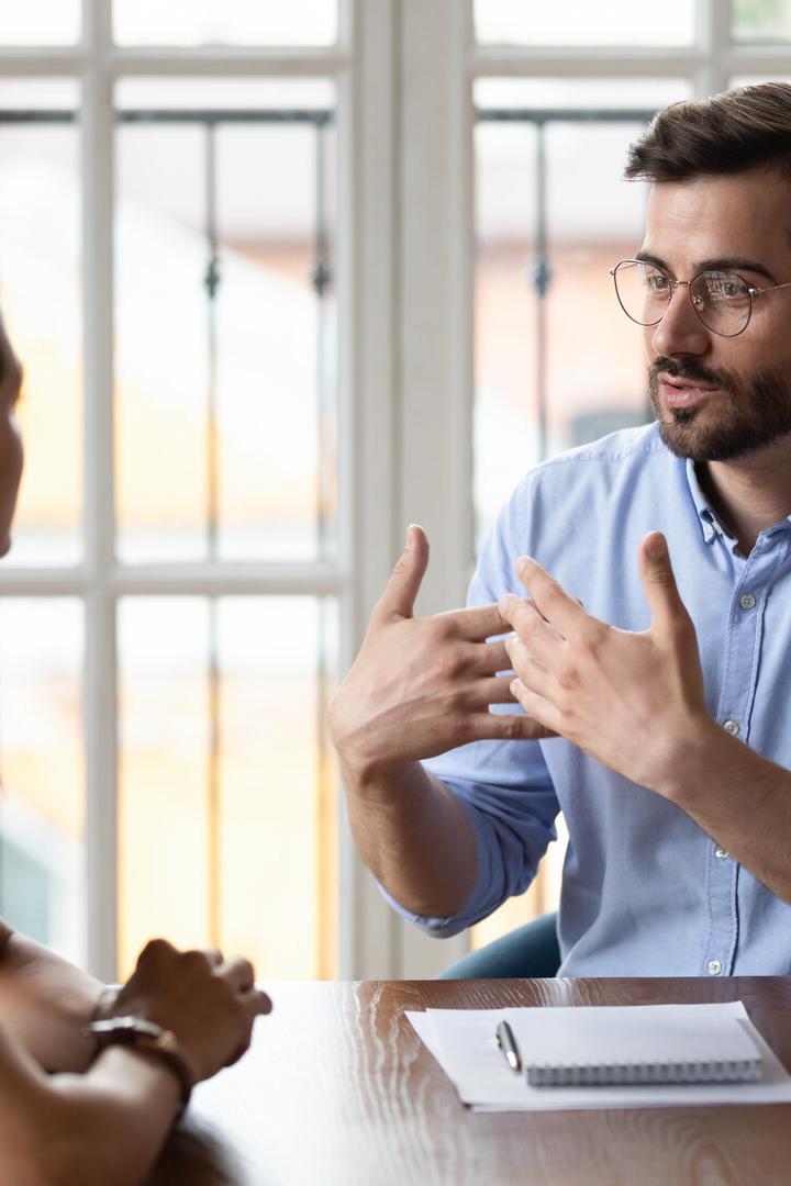 Leader in eyeglasses explaining project details to new female employee.