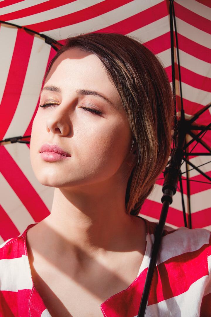 Portrait of a young woman in striped jacket and umbrella.