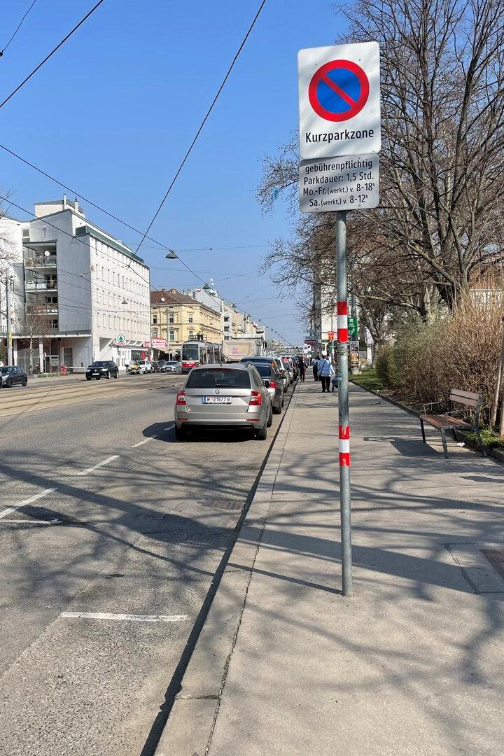 Eine Straße in Wien mit geparkten Autos und einem Kurzparkzonen-Schild.