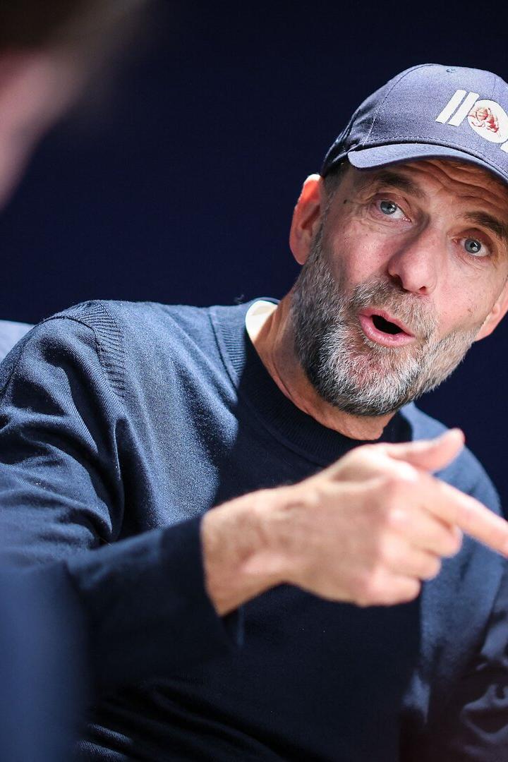Jürgen Klopp trägt eine dunkle Kappe und einen Pullover, während er gestikulierend in einem Gespräch spricht.