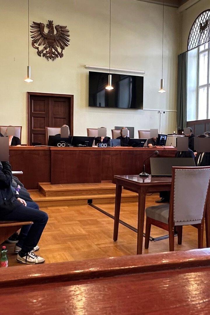 Angeklagte, Verteidiger, Richter und Dolmetsch im Gerichtssaal.