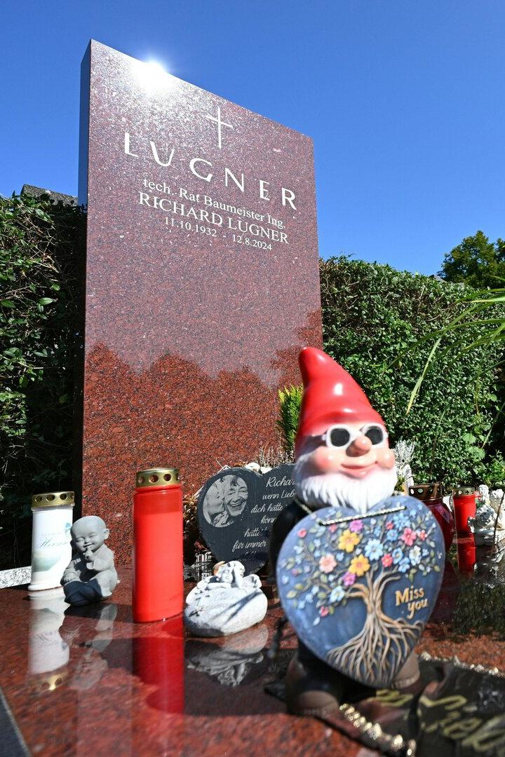 Auf dem Grabstein von Richard Lugner stehen Grablichter, ein Gartenzwerg und ein Topf mit Pflanzen.