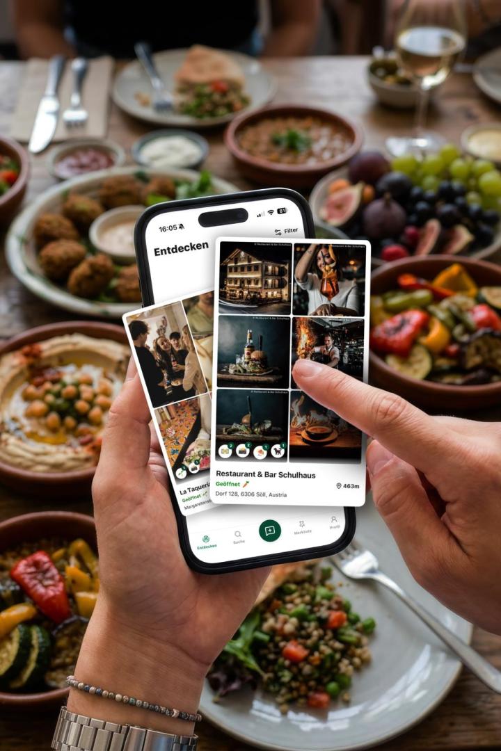 Handy mit Bildern vor mit Essen gefülltem Tisch