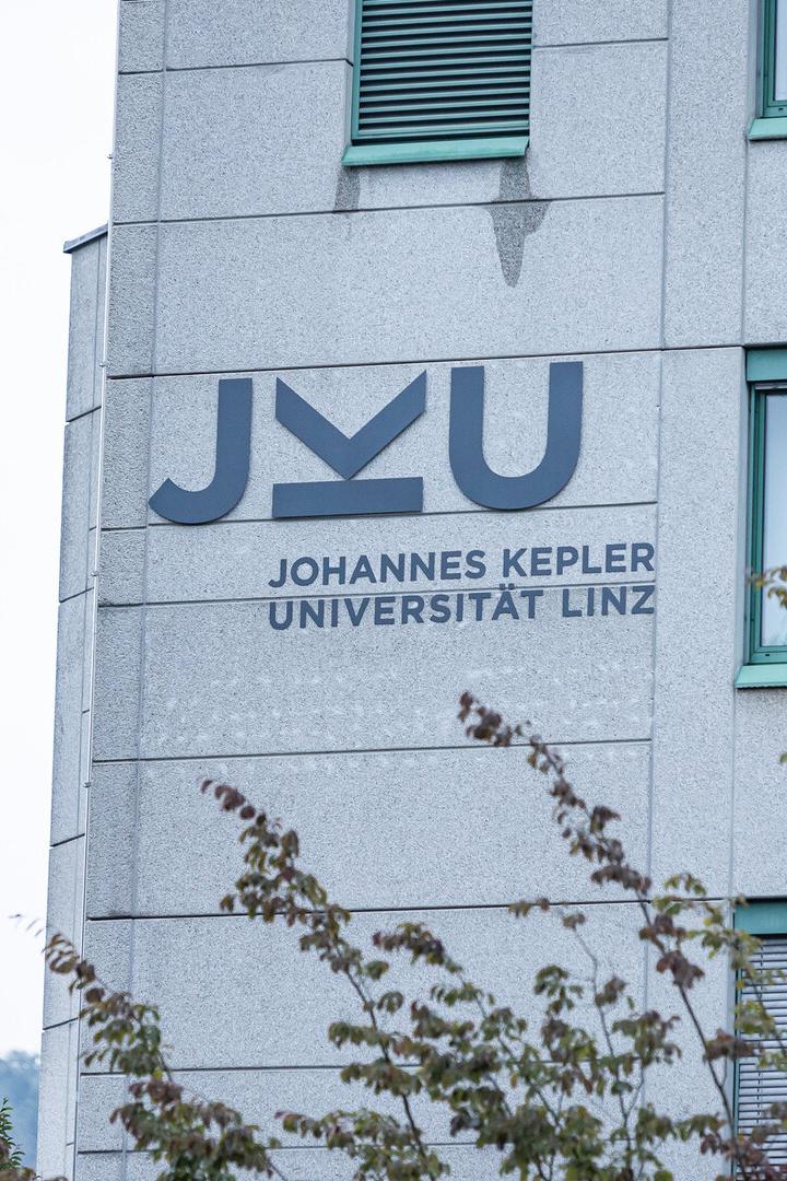 Die Fassade der Johannes Kepler Universität Linz mit dem JKU-Logo ist zu sehen.