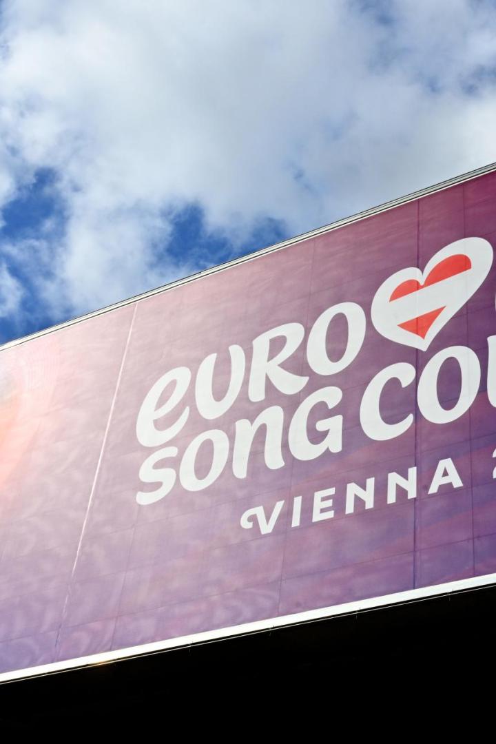 Großes lila Plakat mit der Aufschrift „Eurovision Song Contest Vienna 2026“ und einem stilisierten Herz.