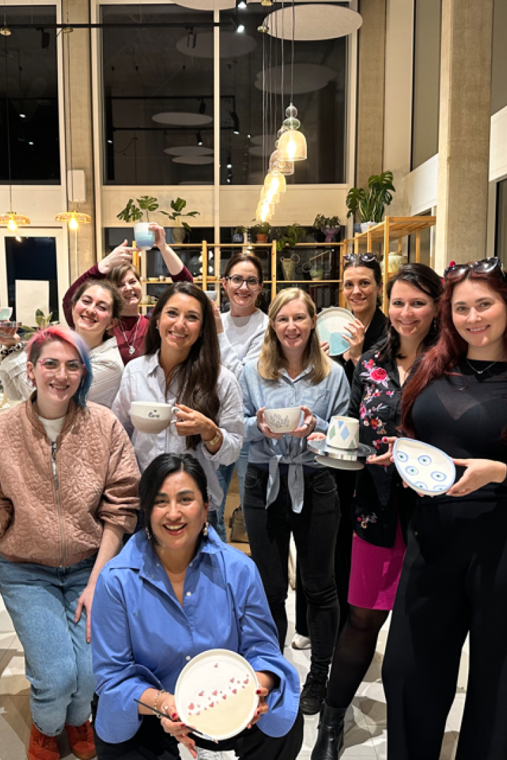 Gruppe von Frauen präsentiert selbst gestaltete Keramik in einem hellen Atelier.