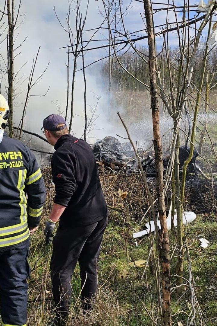 Feuerwehr löscht Wrack in einem Wald