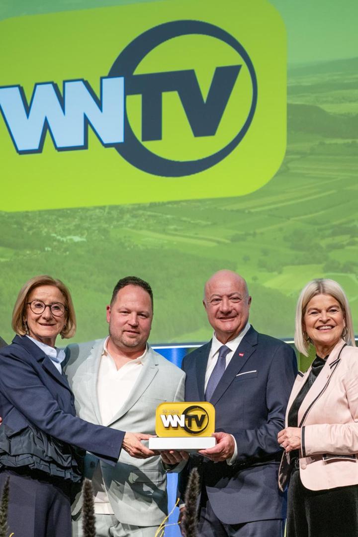 Bürgermeister Klaus Schneeberger, Landeshauptfrau Johanna Mikl-Leitner, Geschäftsführer Bernd Grossmann, Bundeskanzler Christian Stocker, Verteidigungsministerin Klaudia Tanner und Geschäftsführer Erich Lehner stehen vor einem grünen Plakat mit dem Logo von WNTV.
